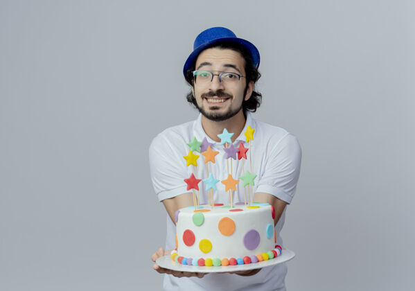 相机笑容可掬的帅哥戴着眼镜和蓝色的帽子 拿着蛋糕对着镜头孤零零地对着白色蛋糕帅气戴着