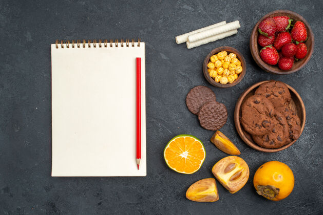 饼干顶视图新鲜的红色草莓和饼干放在深色的桌子上甜甜的糖饼干笔记顶部记事本