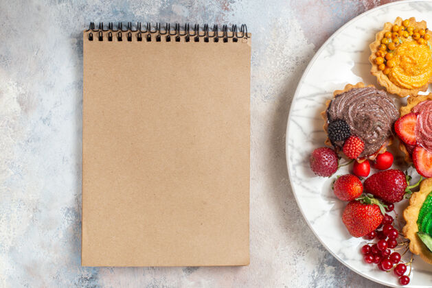 草莓俯瞰美味的奶油蛋糕配水果 放在浅色的桌子上 饼干蛋糕甜点甜笔记本信封早餐