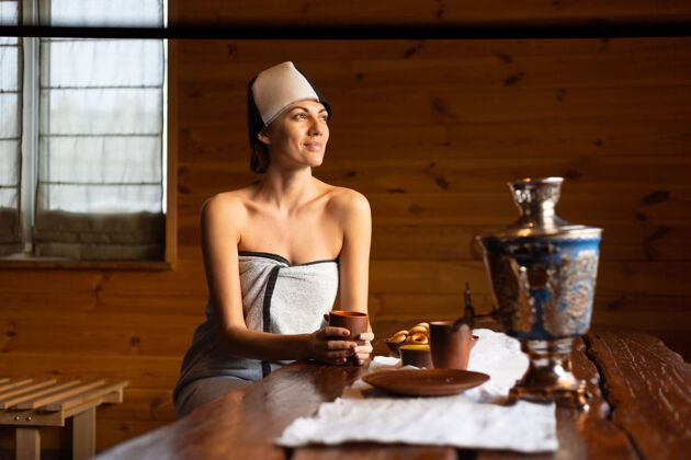 舒适一个戴着帽子的年轻女子坐在一张桌子旁 喝着花草茶 享受着健康的一天水疗美容师咖啡