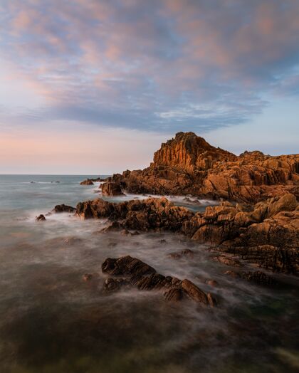 美景在格恩西岛日落的背景下 霍梅顿堡附近岩石海滩的惊人镜头海岸石头奇迹