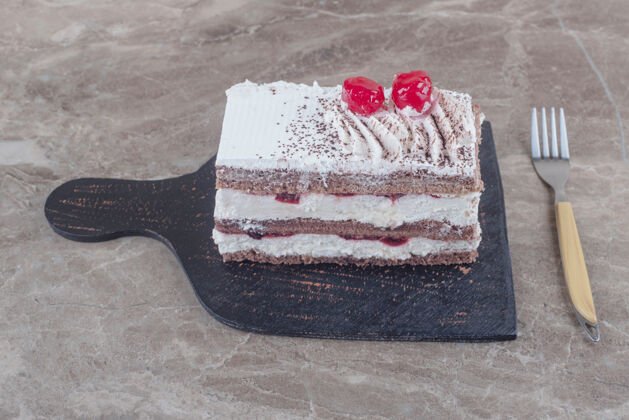 美味小蛋糕片 奶油 樱桃和可可粉放在大理石板上樱桃可口奶油
