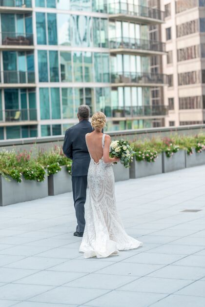 新婚夫妇一对新娘和新郎在美丽的阳台上观看建筑物的垂直镜头礼服浪漫新郎