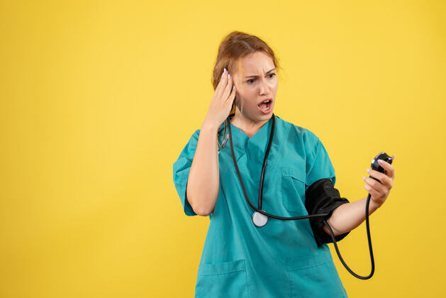 医疗器械身穿医疗服的女医生在黄色墙壁上检查压力的正视图医院医疗听诊器