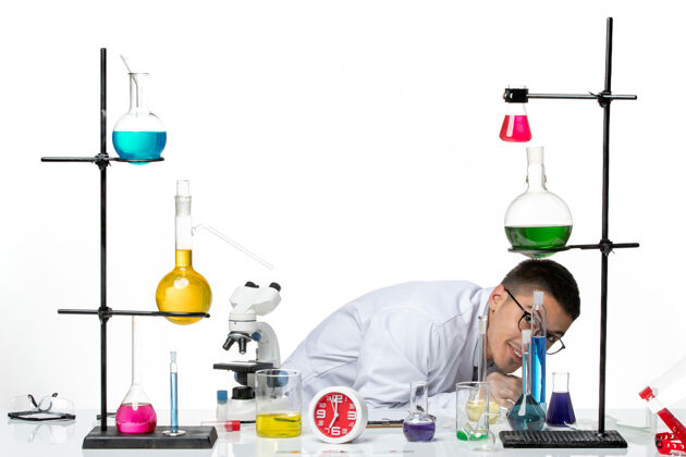 视图前视图穿着白色医疗服的男性化学家坐在白色背景下 躲在病毒科学冠状病毒-大流行实验室医学设备实验室