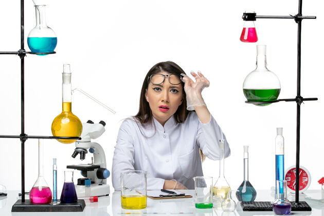 罐子前视图穿着白色医疗服的女化学家正全神贯注地注视着白色背景科学病毒冠状病毒-大流行实验室大流行成人工作