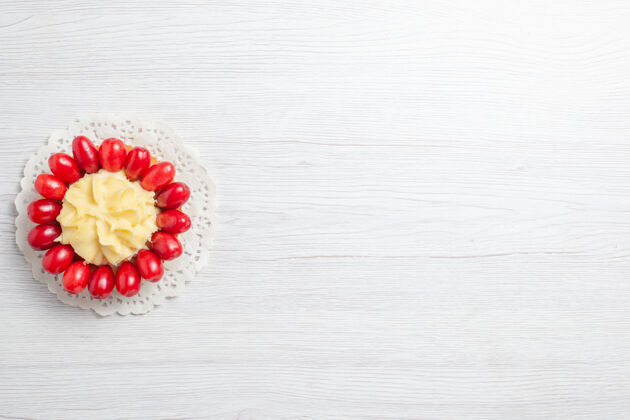 水果俯瞰白色书桌上有山茱萸的奶油蛋糕问候浆果花