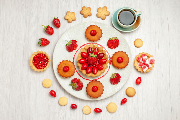 食物俯瞰图：白色桌子上有水果蛋糕和一杯茶餐厅甜点盘子