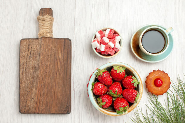 茶俯瞰图：白色桌子上有水果蛋糕和一杯茶杯子多汁草莓