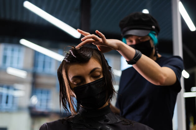 理发师一个专业的女理发师给客户理发这个女孩戴着面具坐在美容院里工人发廊肖像