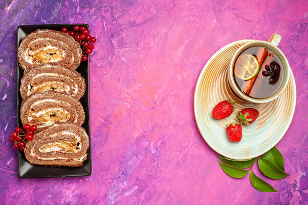 盘子顶视图美味饼干卷和一杯茶放在粉红色的桌子上传统的食物饼干