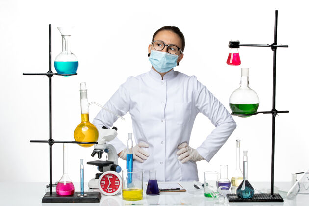 视图前视图：一位身穿医疗服 戴着面具的女化学家正在思考一个白色背景的病毒化学实验室——病毒飞溅化学外套西装