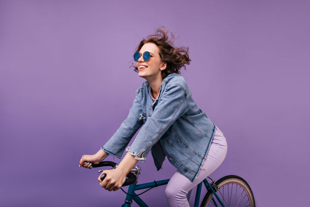 美丽黑发快乐的女士骑在自行车上发抖迷人的高加索女孩卷发坐在自行车上车辆肖像爱好