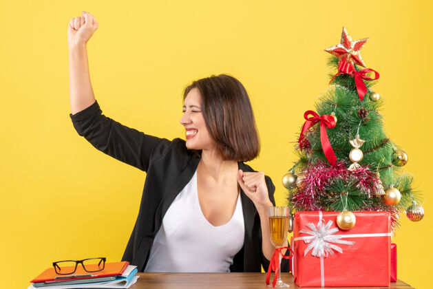 欢呼圣诞气氛与年轻的商业女士享受她的成功自豪的黄色快乐人人