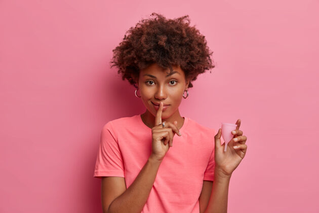 月女性健康卫生理念神秘女性摆出实用环保的月经杯插入阴道 食指贴在嘴唇上 做出安静的姿势 说明产品的优点干净严重可重复使用