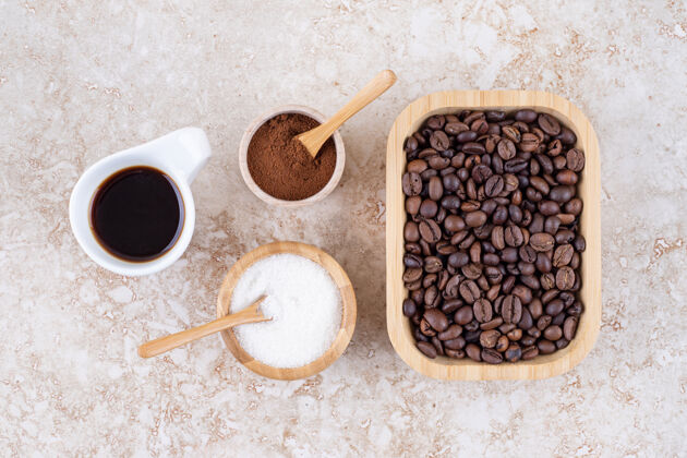 碗把咖啡杯 糖 磨碎的咖啡粉和一堆咖啡豆放在一个木盘里粉末芳香研磨