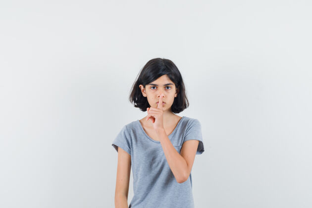女性小女孩在t恤衫上显示出沉默的姿态 看上去很小心 正面视图表演人小