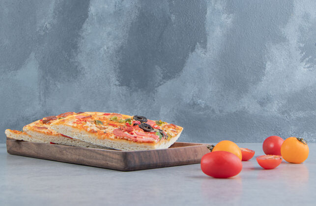 香肠比萨片放在托盘上 旁边是大理石上的小西红柿橄榄美味比萨饼