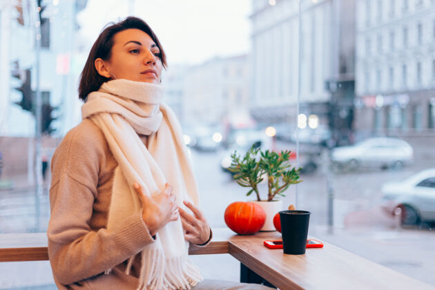 肖像一个女孩在舒适的咖啡馆里用一杯热咖啡取暖冬天桌子咖啡店