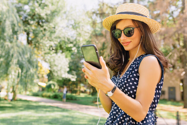女孩可爱的快乐女人使用智能手机 享受在公园散步女性春天积极