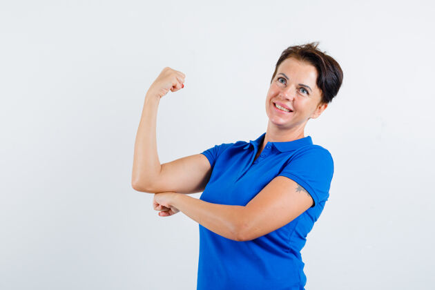漂亮身着蓝色t恤的成熟女性 展现手臂肌肉和自信 正面视图肌肉老年人健康