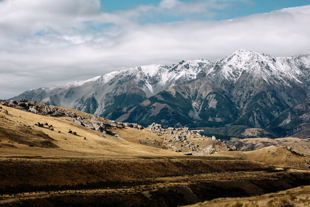 覆盖新西兰南岛的乡村景色被白雪覆盖的群山吹响多云天空草
