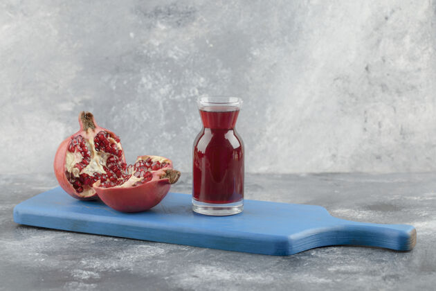 新鲜一杯新鲜的果汁和成熟的石榴水果放在蓝板上成熟水果种子