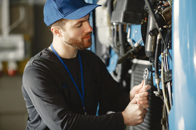 人汽车修理工在车库里用工具修理蓝色的汽车人车辆工作
