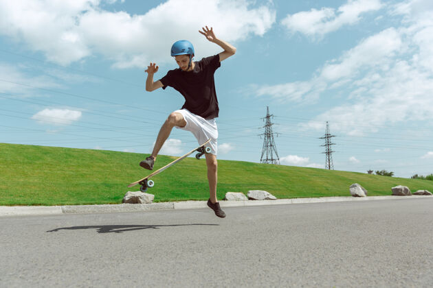 锻炼在阳光明媚的日子里 在城市街道上玩滑板的人年轻人在草地附近骑马 玩长板休闲活动 运动 极限 爱好和运动的概念乐趣公园速度