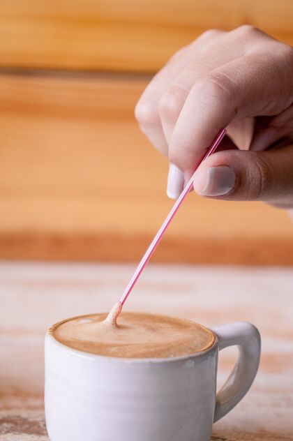休息垂直选择性聚焦拍摄一个人把一根棍子放在一杯咖啡里桌子早餐暖的
