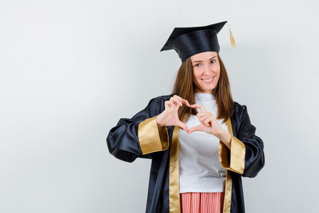 女性毕业的女人穿着休闲服展示心形 制服 看起来很高兴成就年轻衣服