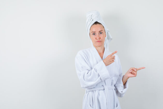 拼图身穿白色浴袍的年轻女子 毛巾指着右边 神情困惑 正对着前方健康清醒优雅