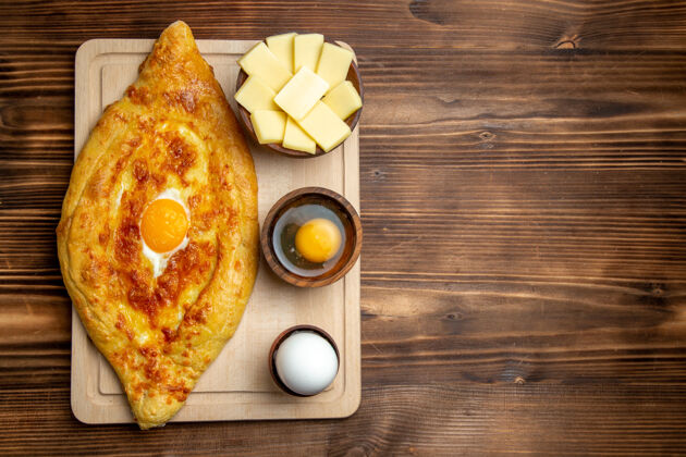 书桌顶视图棕色木制书桌上的新鲜烤面包和熟鸡蛋面包面团餐面包早餐鸡蛋食品面包顶部餐