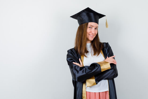手臂毕业的女人穿着休闲服 穿着制服 双臂交叉站着 看起来很自信 前视帽子年轻大学