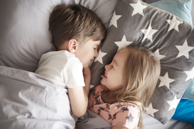 卧室睡在她哥哥旁边的小女孩的特写肖像闭上眼睛童年躺下