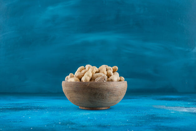 坚果花生壳在碗里放在蓝色的表面上营养美味蛋白质