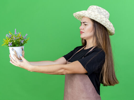 园艺想着漂亮的园丁 穿着制服 戴着园艺帽的女孩 在绿色的背景上 把花盆里的花隔离开来帽子穿制服