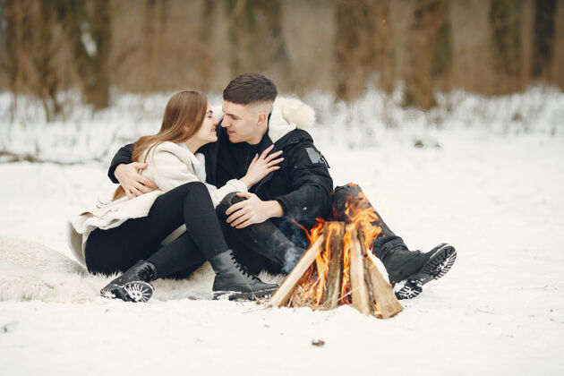 雪生活方式拍摄的一对夫妇在雪林人们在户外度过寒假人们在篝火旁情侣寒冷关系