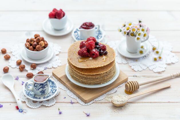 自制高角度特写镜头的生素食煎饼与蜂蜜和浆果健康美味雏菊