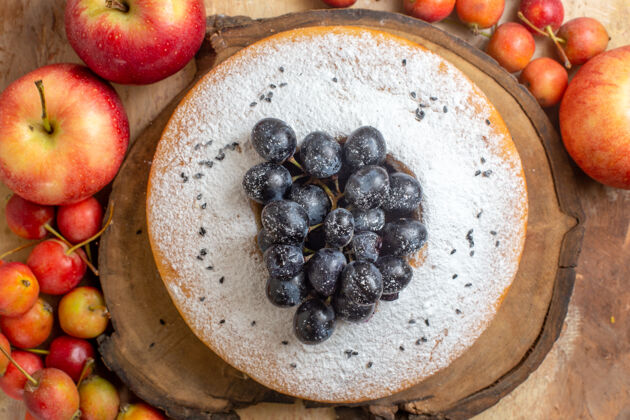 新鲜顶部特写视图浆果苹果和浆果围绕着一个蛋糕和葡萄在木板上甜点特写水果