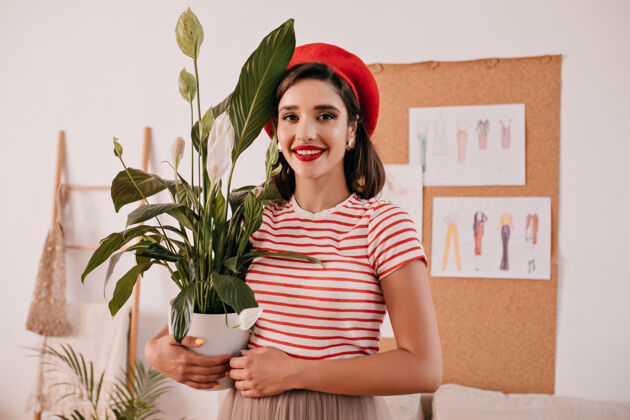优雅身着条纹衬衫的女士的肖像中有一株植物穿着浅色t恤和红色贝雷帽的漂亮女士手拿鲜花在镜头前摆姿势巴黎女士白色