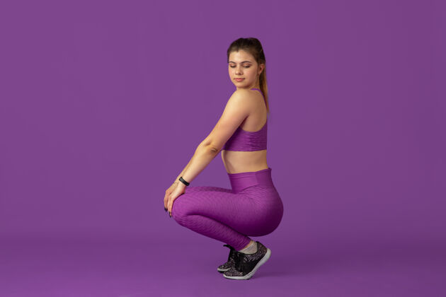 体重格蕾丝美丽的年轻女运动员在工作室练习 单色紫色肖像杠铃广告举重