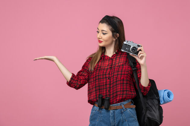 拍摄正面图：年轻女性用相机在粉色背景上拍照-女模特相机成人脸