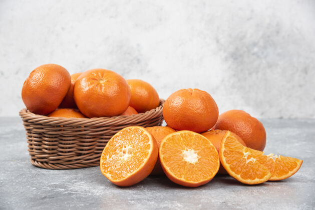 组把新鲜多汁的橙子全切在放在石桌上的柳条篮子里有机水果橙子片