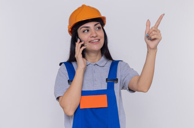 头盔身穿施工制服 头戴安全帽的年轻建筑妇女向旁边看电话建筑手机