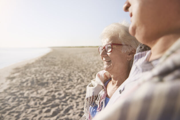 太阳老年夫妇在沙滩 退休和暑假的概念祖父妻子夏天