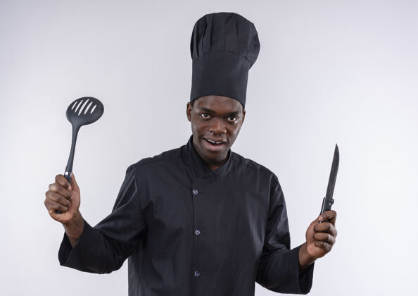 烹饪身着厨师制服的年轻美籍黑人厨师手持小刀和抹刀 白色带复印空间抹刀复制厨师