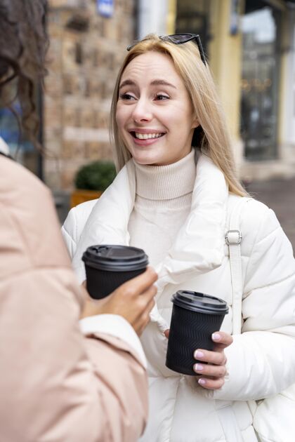 户外用咖啡杯接近女人城市城市旅行者