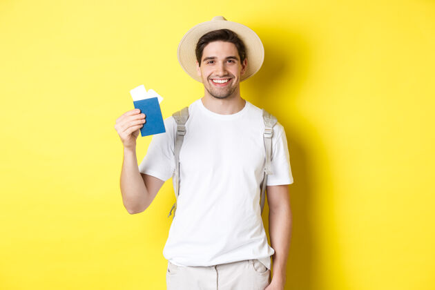 男人旅游度假年轻微笑的游客拿着机票 拿着护照 在黄色的背景下旅行工作室表情站着