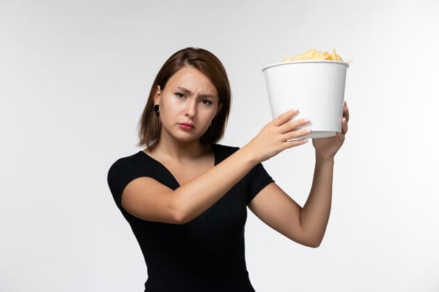 孤独正面图：年轻的女性拿着薯片 在白色的桌子上看电影电影院书桌剧院